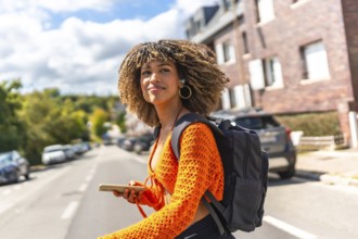 Side view of a beauty latin woman walking along street using mobile phone to get directions with