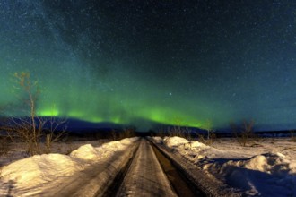 A beautiful Northern Lights in the cold Icelandic winter at night on a snowy trail. Aurora Borealis