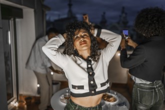 Sensual woman dancing during night roof party with diverse multi-ethnic friends