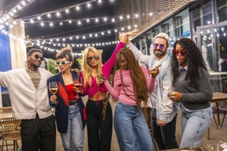 Modern multi-ethnic young people celebrating party outside a bar at night