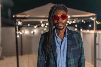 Portrait of a cool african man with afro hairslyle and colorful vintage jacket and sunglasses