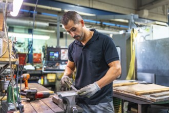 Caucasian adult male manual worker working in metal factory using drill and manual tools
