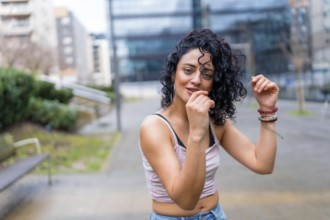 Stylish young woman with curly hair enjoying dancing outdoors, showcasing urban lifestyle and