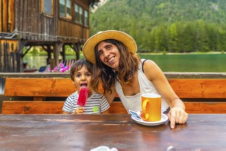 Tourists enjoying a summer day with ice cream and coffee by a mountain lake in the italian alps