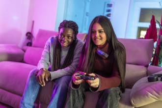 Two friends enjoying their free time playing with a gamepad sitting on a sofa in a colorful living