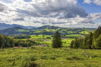 Picturesque mountain landscape with green meadows, wooded hills and impressive clouds in the sky,
