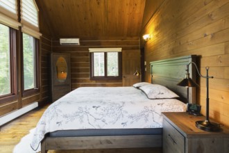 King size bed on wood-frame with wooden headboard, nightstand with antique industrial style lamp,