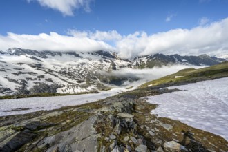 Mountain landscape with snowfields and high fog in the valley, behind summit Hoher Weißzint and