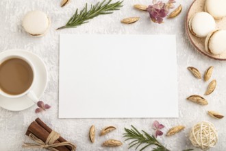 White paper sheet mockup with cup of coffee, almonds and macaroons on gray concrete background.