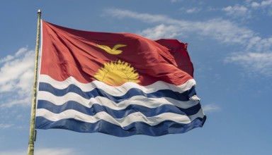 The flag of Kiribati, Polynesia, flutters in the wind, isolated against a blue sky