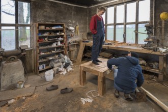 Young man tests the durability of his Tiasch in the workshop, his father looks on,