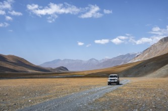 Off-road vehicle on gravel track, Burkhan mountain valley with meandering river, barren dramatic