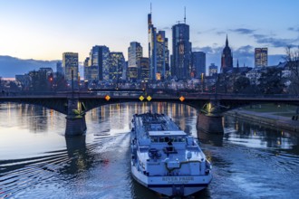 Skyline of the city centre of Frankfurt am Main, river Main, dusk, Ignatz-Bubis-Bridge, cargo ship,