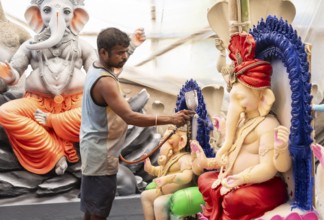 An artisan decorates an idol of the elephant-headed Hindu deity Ganesha at a workshop ahead of the