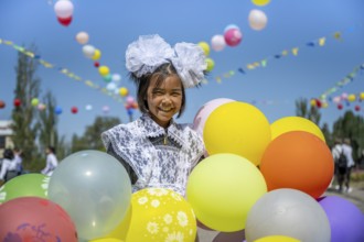 Happy schoolgirl with colourful balloons on the first day of school, Issyk-Kul region, Kyrgyzstan,
