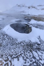 Hot springs and geothermal area in front of a mountain landscape in winter, cloudy mood, Hverir,
