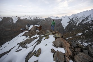 Mountaineer looking at mountain panorama and glacier, mountain hut Ramolhaus in autumn with snow,