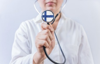 Female doctor holding stethoscope with Finland flag. Finland Health and Care Concept