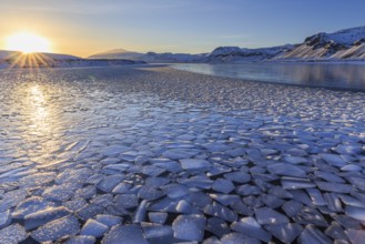 Ice floes on a lake in front of snowy mountains, sunset, backlight, evening light, snow, winter,