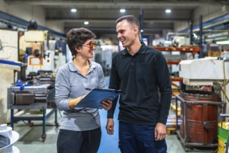 Female boss and worker talking happily and animatedly in a cnc factory