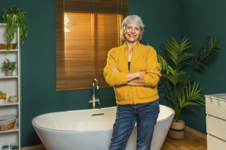 Casual caucasian mature woman standing with arms crossed on a modern bathroom