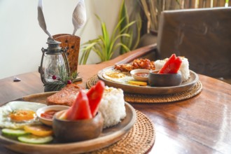 Two plates of filipino breakfast featuring tocino, fried rice, fried egg, watermelon, cucumber, and