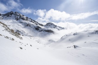 Atmospheric clouds in a wintry mountain landscape, ascent to Porta d'Es-cha, Bündner Haute Route