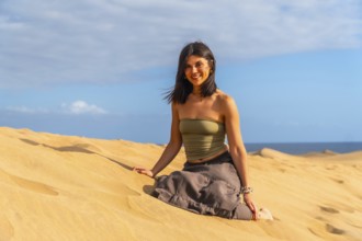 Young woman relaxing and enjoying a sunny day sitting on the sand of the maspalomas dunes in gran