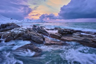 Waves of Norwegian sea on rocky coast in fjord on sunset with sun. Skagsanden beach, Lofoten