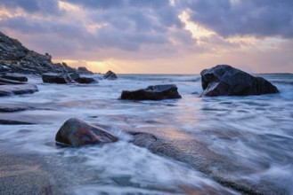 Rocks on beach of fjord of Norwegian sea in winteron sunset. Utakliev beach, Lofoten islands,