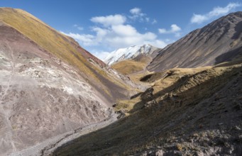 Valley with mountain stream between high mountains in autumn, mountain landscape with glaciated