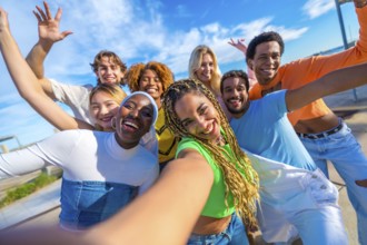 Multi-ethnic friends smiling at camera while taking a funny selfie in the city