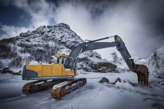 Old excavator with excavator bucket in winter. Road construction in snow. Lofoten islands, Norway,
