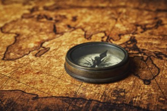 Old vintage retro compass on ancient world map close up