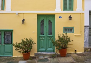 A charming house with a yellow facade and green doors in the Plaka district of Athens, Greece,