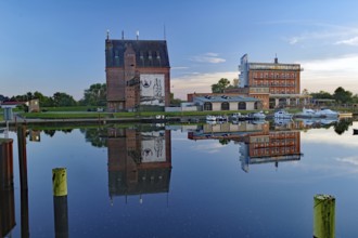 Historic buildings on the waterfront with boats and reflected evening sky in calm harbour water,