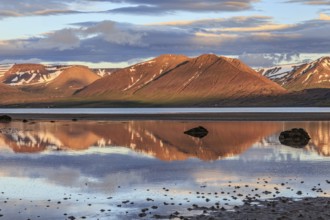 Fjord, low tide, stones, mountains reflected in the water, evening light, cloudy mood, Thingeyri,