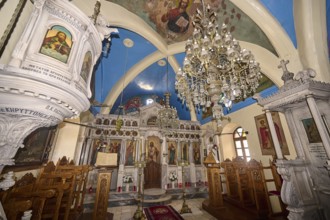 A magnificently decorated church interior with chandeliers, an ornate altar and colourful icons,