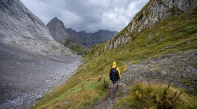 A mountaineer on a hiking trail with lush green vegetation, hiking trail to the Wolayerseehütte,