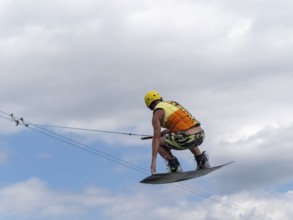 Sporty man with jump with wakeboard, water sports, water skiing and wake park