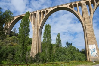 Steinbrücke mit großen Bögen über einem Wald, blauer Himmel und weiße Wolken, Aquädukt, Guadalupe,