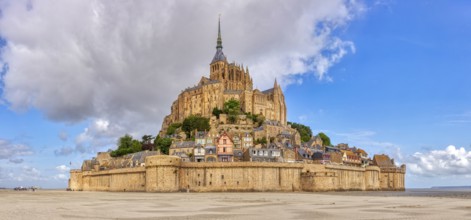 Impressive abbey on an island in the middle of a vast sandy landscape under a blue sky, Le