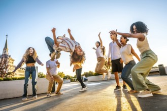 Man jumping dancing free style surrounded by multi-ethnic friends in the city during sunset