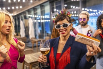 Woman celebrating birthday with fiends holding a beer and a cake outside a bar at night