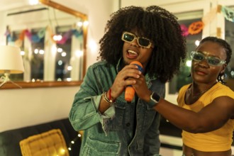 Latin man singing karaoke helped by woman at night party at home