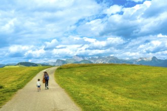 Mother and child walking on a path at alpe di siusi enjoying the landscape in the dolomites on a