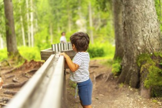 Curious kid having fun with water game in the forest of lake braies, famous destination in
