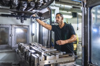 Male caucasian technician working with milling machine in a cnc metallurgic factory