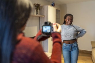 Photographer capturing her beautiful friend posing joyfully in the cozy living room, celebrating