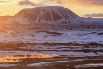 Hot springs and geothermal area in front of mountain landscape in winter, sunbeams, cloudy mood,